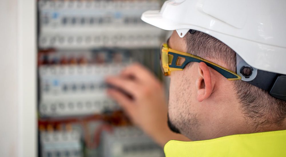 electrical-technician-looking-focused-while-working-switchboard-with-fuses